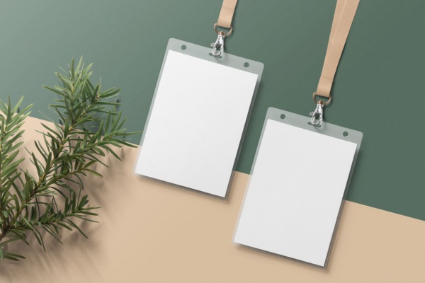 Two blank ID cards with beige lanyards on flat surface.