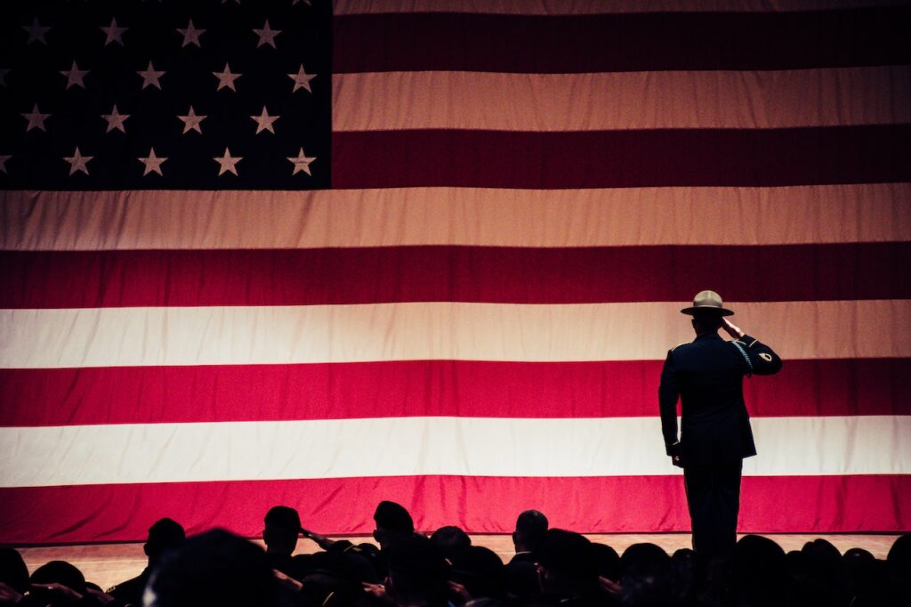 active duty servicemember standing in front of US flag