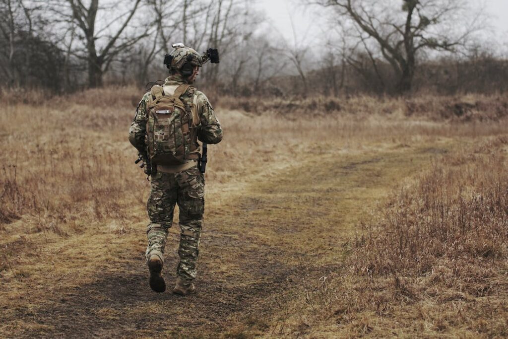 Military personnel walking on brown grass field