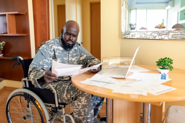 Disabled veteran in wheelchair reviewing documents at home office