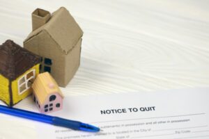A "Notice to Quit" document with small house models and a pen.