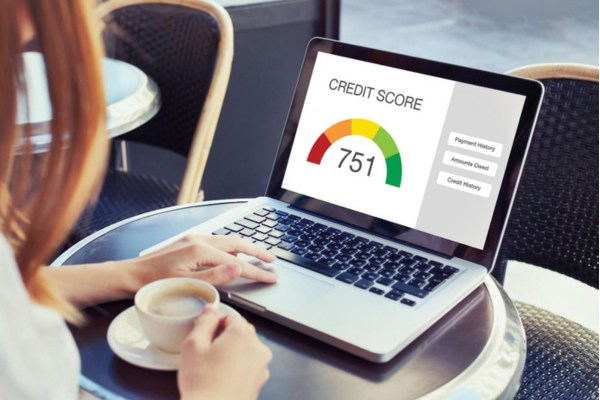 Woman checking credit score on laptop while drinking coffee.