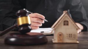 Judge gavel and house model on the table man signing in document