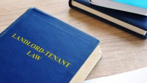 Blue book titled "Landlord-Tenant Law" on wooden desk.