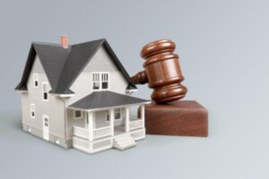 Wooden judge gavel and toy house on background