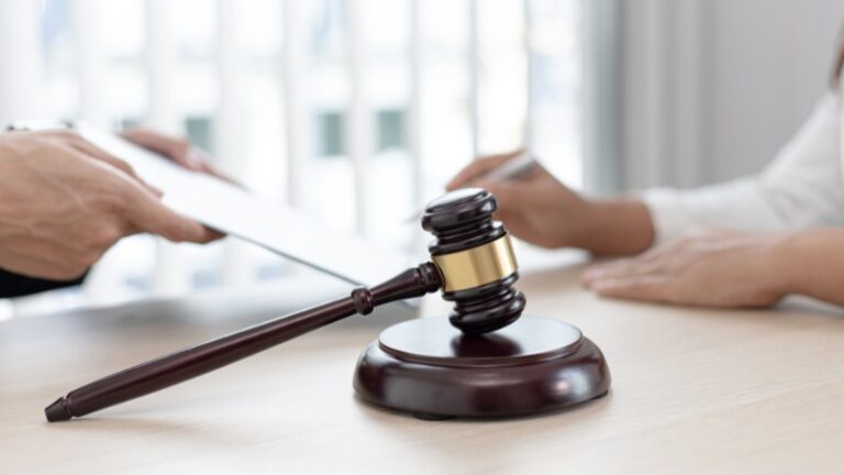 Judge’s gavel on table during legal document signing process.