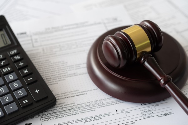 Judge’s gavel placed on financial documents with a calculator nearby.