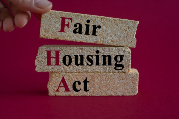 Hand holding wooden blocks spelling Fair Housing Act letters.