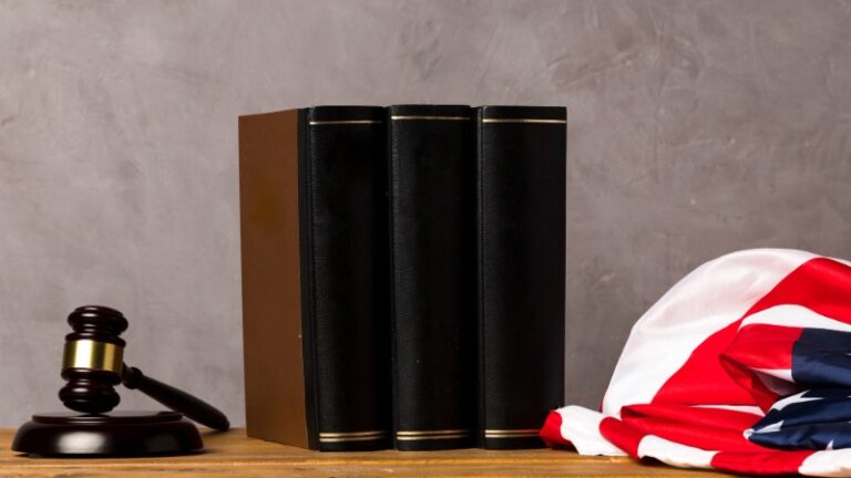 Gavel, legal books, and American flag on wooden desk.