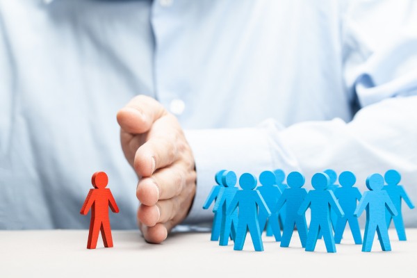 Hand separating a red figure from a group of blue figures, symbolizing discrimination.