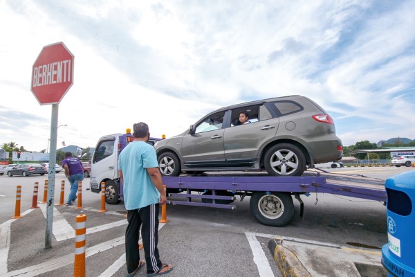 Car repossessed onto tow truck at stop sign.