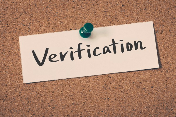 Verification note pinned on corkboard with green pushpin.