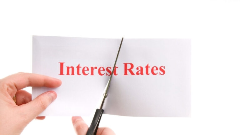 Hands cutting paper labeled interest rates