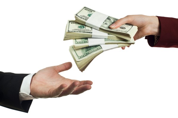 Person handing over bundles of cash to another person.