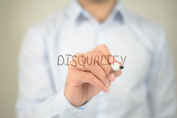 Person writing the word “Disqualify” on clear glass surface.