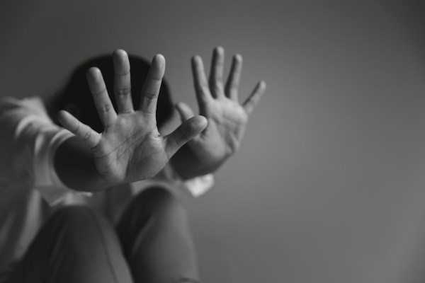 Frightened person raising hands to block in self-defense.