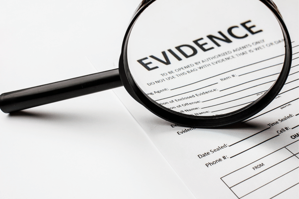 A magnifying glass placed over an evidence form highlights details for an investigation or legal case.
